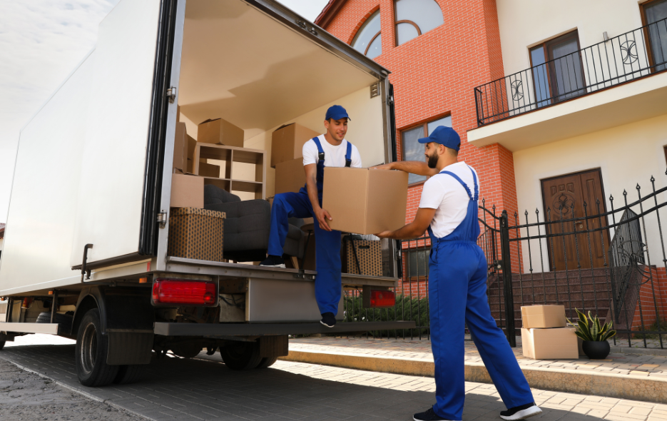 Two men wearing overalls taking boxes out of the back of a lorry